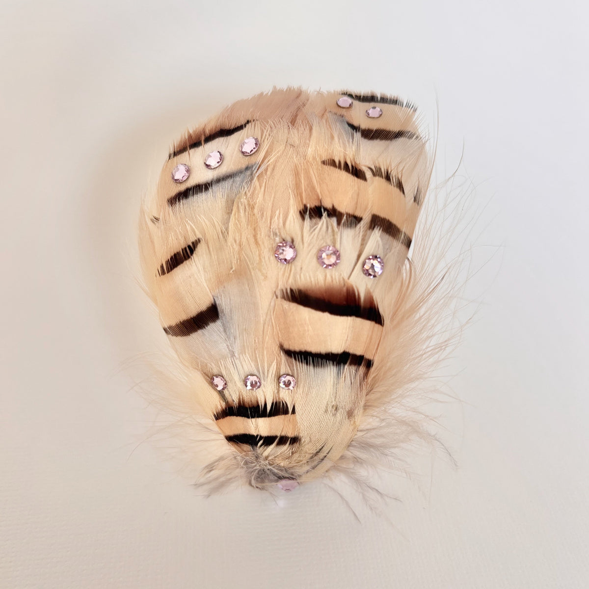 Handmade beige and brown asymmetrical feather hair clip and brooch with natural striped pattern and pale pink Swarovski crystal detailing by Nicole Ho.