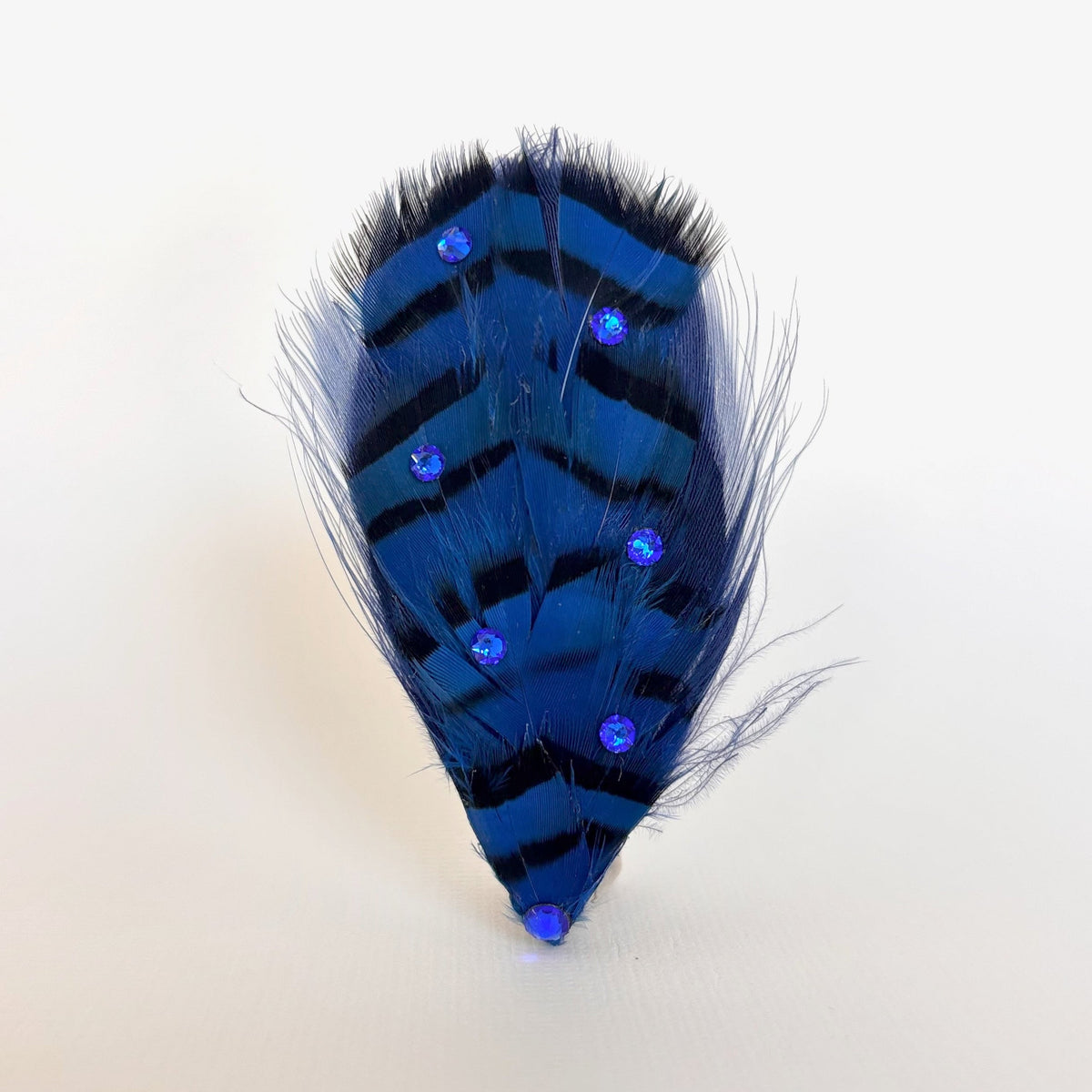 Handmade blue and black feather hair clip and brooch with vivid natural feather pattern and blue Swarovski crystal detailing by Nicole Ho.