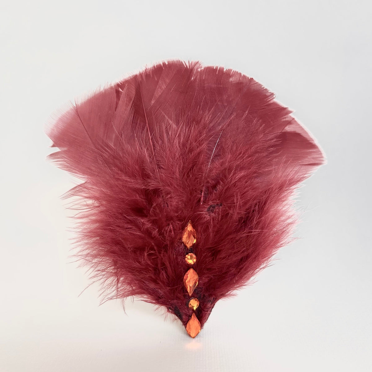 Handmade burgundy feather hair clip and brooch with layered feathers, soft fluffy texture and orange Swarovski crystal detailing by Nicole Ho.